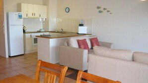 A compact living space with a kitchenette, a dining area with a table and chairs, and a sofa. - Sails Resort on Golden Beach Unit 03 (Golden Beach)