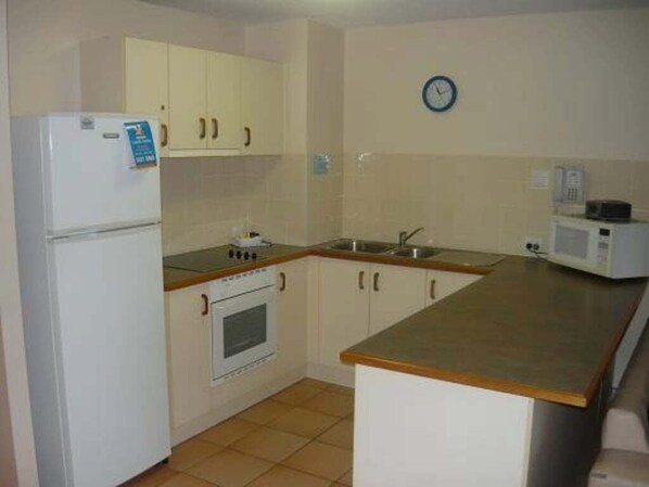 A compact kitchen with white cabinets, a built-in oven, a microwave, and a sink.