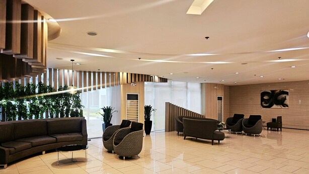 A spacious lobby with a curved sofa, round seating, and a staircase leading to upper floors. - Charm's City Escape at Grace Residences (Taguig)