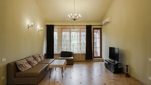 A living room with a sofa, a coffee table, a TV stand, and a chandelier.
