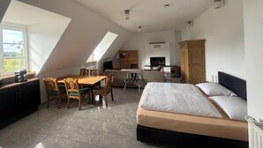 A modern loft bedroom with a sloped ceiling, a dining area, and a kitchen. - Hof König, apartment 4, 76 m2, 1-6 persons (Everswinkel)