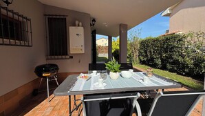 Eine Außenpatio mit Tisch, Stühlen, Grill und Warmwasserbereiter.