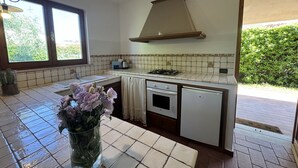Eine Küche mit gefliestem Rücksprühen, einem Gasherd, einer Spüle und einem Geschirrspüler. Ein Fenster sorgt für natürliches Licht und bietet Blick auf Grünfläche.