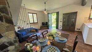 Ein Essbereich mit einem für vier Personen gedeckten Tisch, umgeben von Steinwänden und einem blauen Sofa.