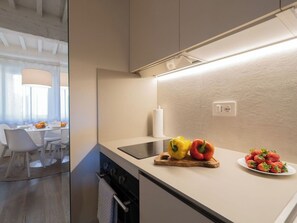 A modern kitchen with a built-in oven, a cutting board with bell peppers, and a plate of strawberries.