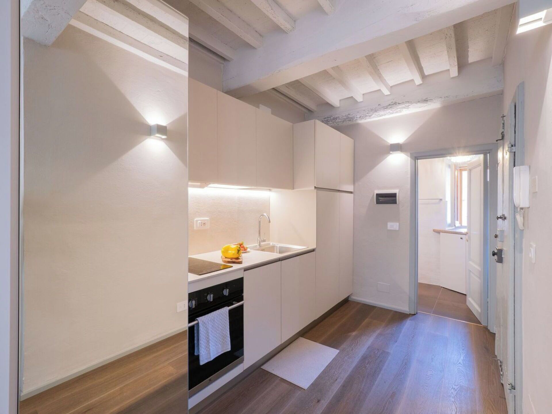 Cuina estreta amb forn de mur, un rentapeus i una petita encimera. Té un terra de fusta i una porta que dona a una altra habitació.