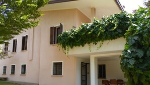 Un edificio con una zona de estar al aire libre cubierta, una puerta y ventanas.