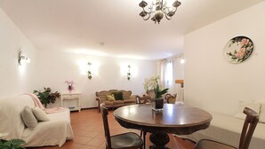 Un comedor con una mesa redonda de madera, dos sillas, un sofá y una lámpara de araña.