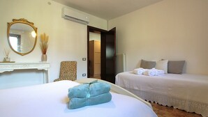 Habitación de hotel con dos camas, un espejo, aire acondicionado, una silla y un radiador.