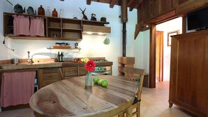 Una cocina rústica con armarios de madera, una mesa redonda de madera y una estufa.