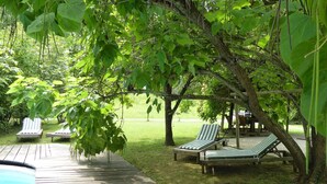 Una terraza de madera con sillones de descanso y una piscina.
