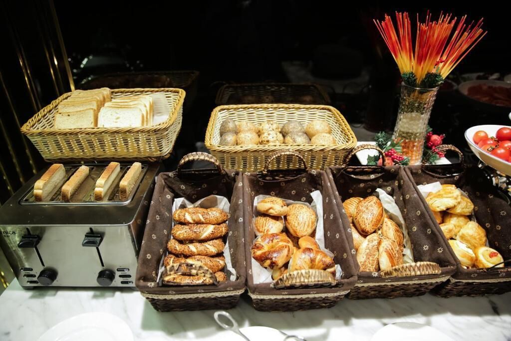 Une table de buffet proposant une variété de produits de boulangerie, notamment du pain, des viennoiseries et des petits pains.
