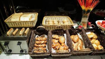 Une table de buffet proposant une variété de produits de boulangerie, notamment du pain, des viennoiseries et des petits pains.