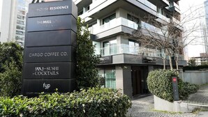 Ein modernes Hotel mit mehreren Etagen, eine Schautafel für The House Residence, The Mill Hotel, Cargo Coffee Co. und ein Restaurant für Sushi und Cocktails.