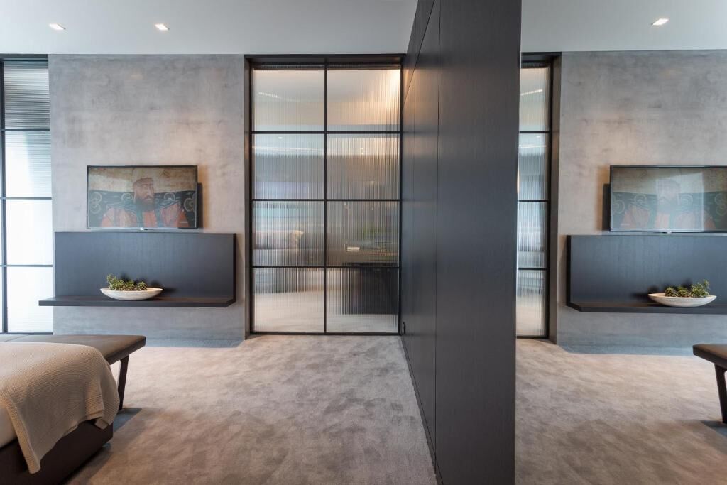 A modern interior with a large sliding door, two wall-mounted TVs, and a bench with a cushion.