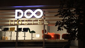 Placa de hotel com o nome 'Doo Hostel' e a exibição de várias cadeiras.