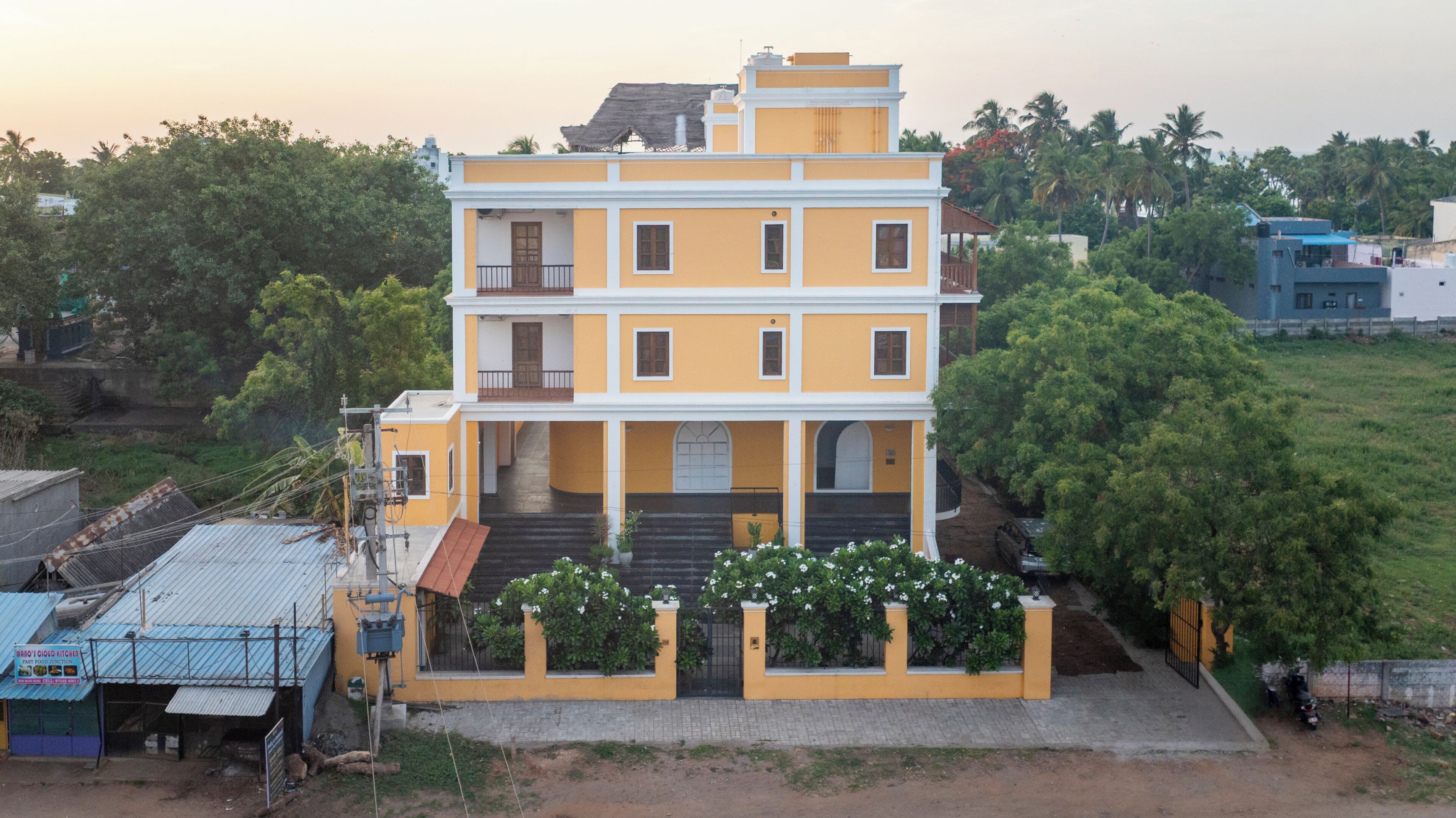 A multi-story building with a yellow facade, a central entrance with steps, and a gated entrance.