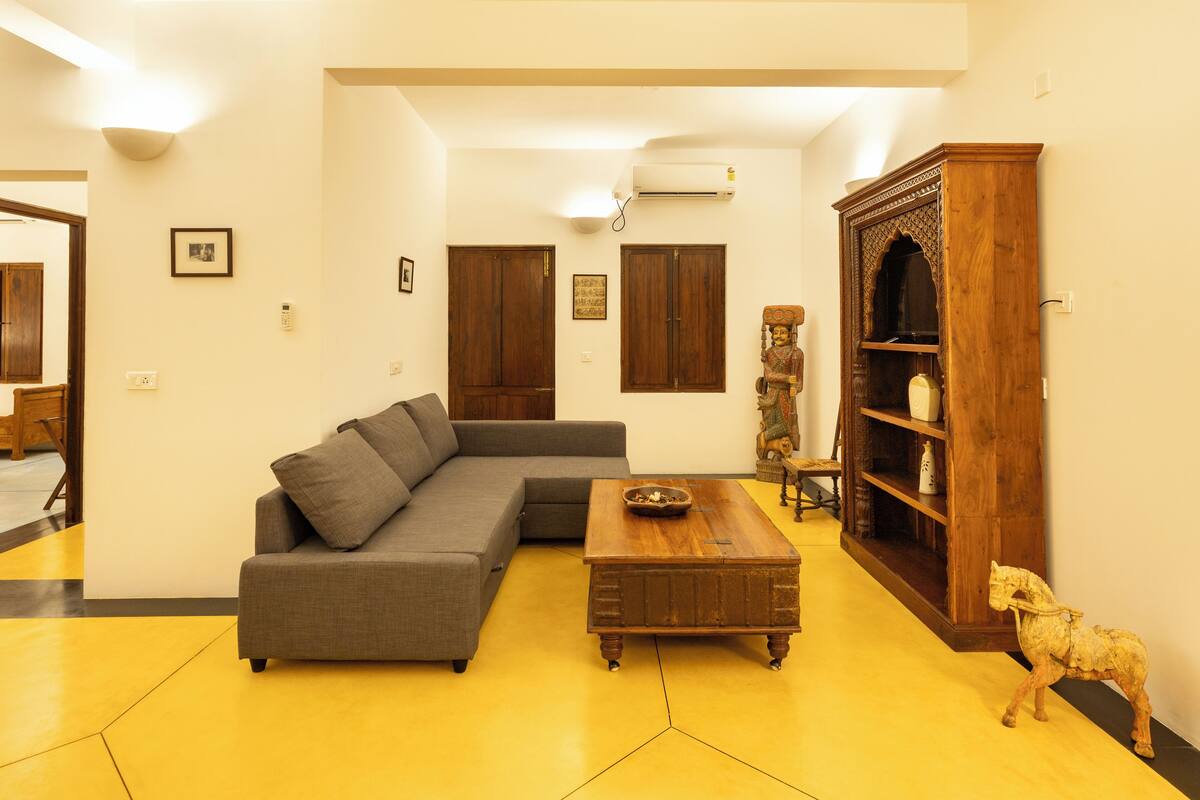 A living room with a sectional sofa, a wooden coffee table, and a decorative cabinet.