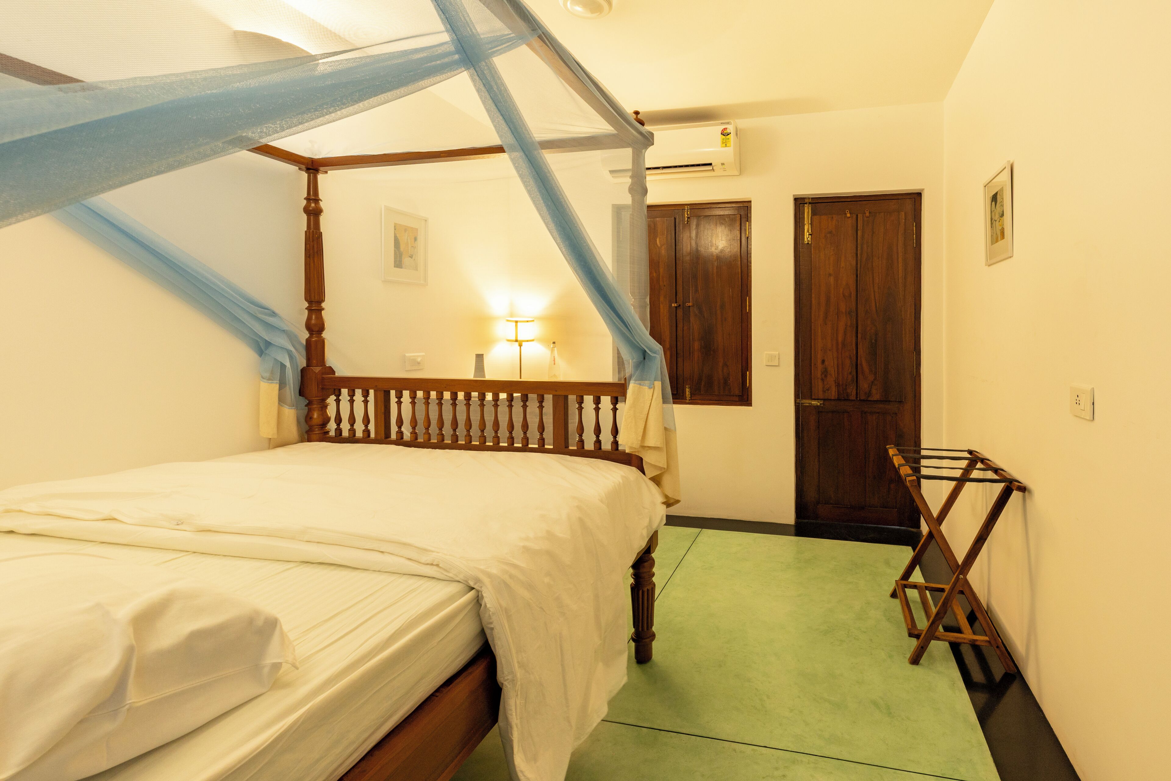 Un dormitorio con cama con dosel, una lámpara de noche, un armario de madera y suelo verde.