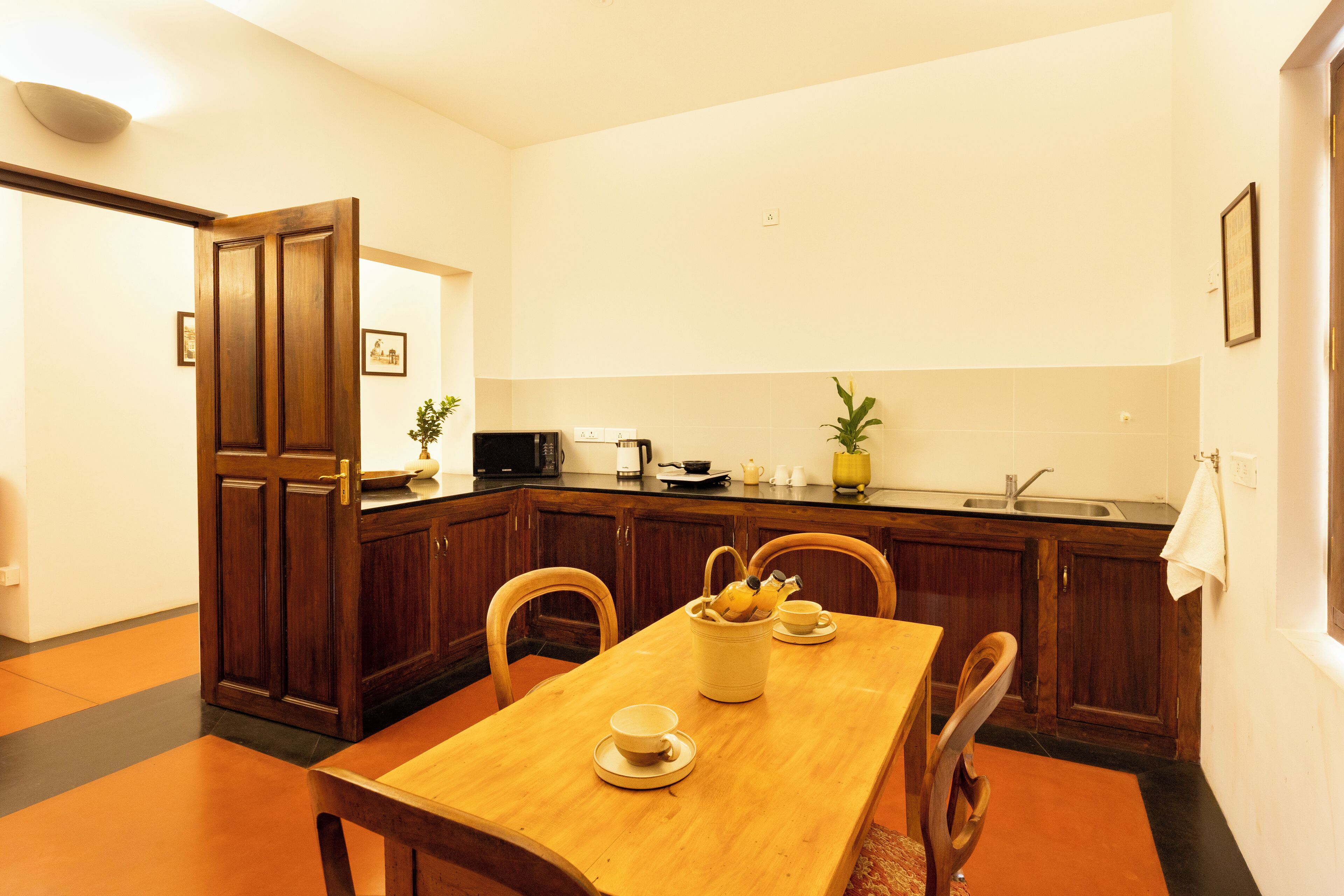 Un comedor con una mesa de madera, sillas, un cuenco de fruta y una cafetera.