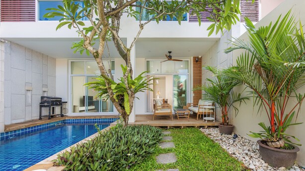 A modern outdoor pool area with a glass-enclosed patio, seating, and potted plants. - Villa Aura 3BR Private Pool Near Naiharn (Rawai)