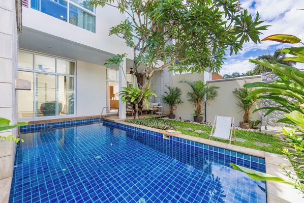 A modern house with a swimming pool, surrounded by lush greenery and a well-maintained garden.