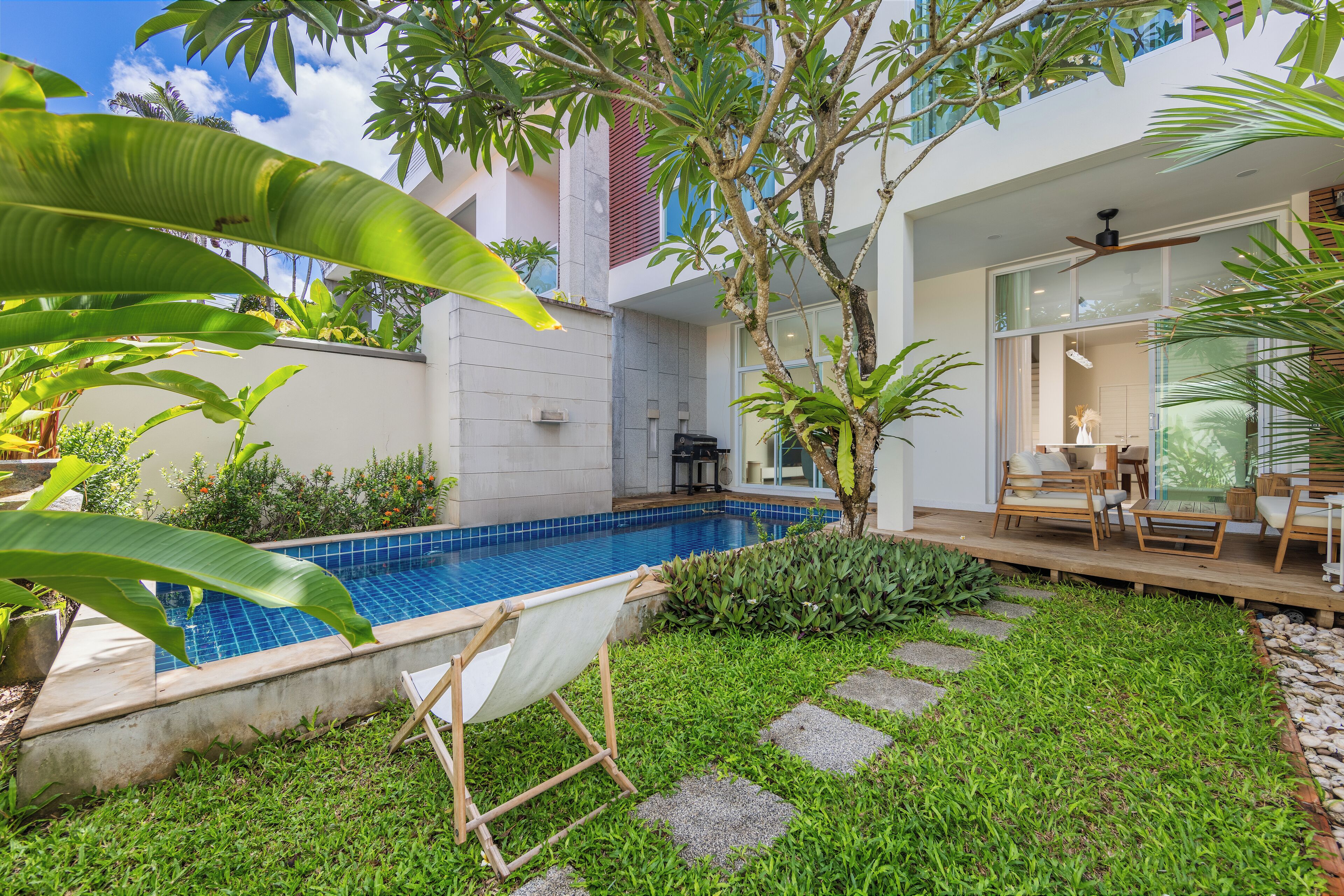 A modern outdoor pool area with a hammock, stone steps, and lush greenery.