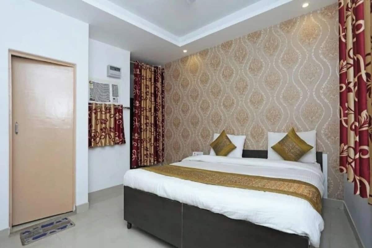 A bedroom with a bed, curtains, and a patterned wall.