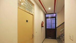 A hallway with a yellow door, a fire extinguisher, and a staircase with metal railings.
