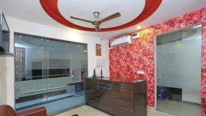 A reception area with a wooden desk labeled "RECEPTION," a ceiling fan, and a patterned wall.