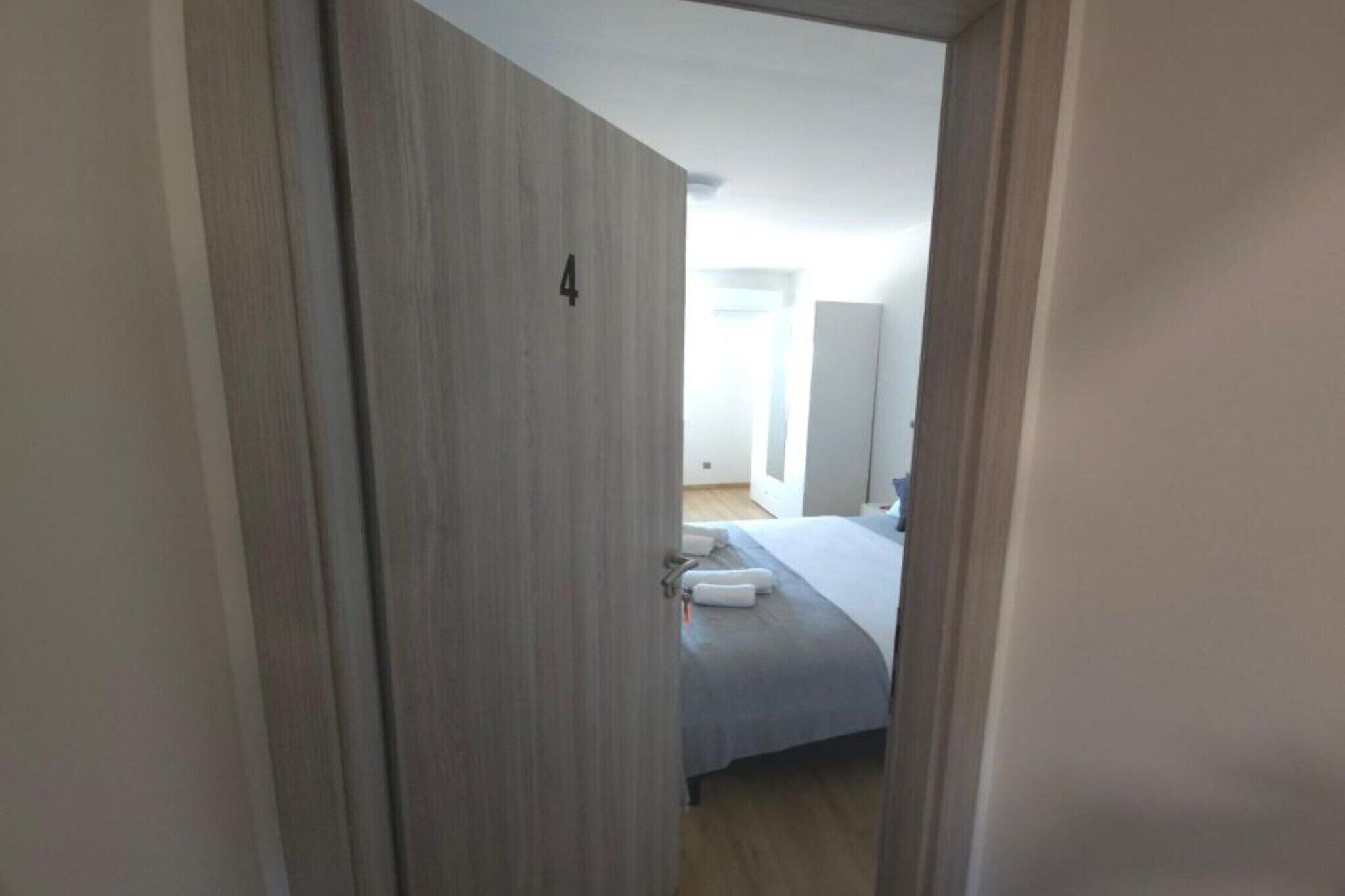 A hotel room with a bed, a bedside table, and a wardrobe.