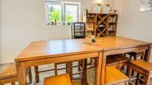 A wooden dining table with benches, a bookshelf, and a window with a view of greenery. - Rooms Burnum - Twin Room 7 (Vrbnik-Knin)