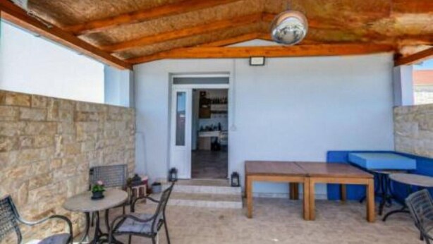 An outdoor patio area with a wooden ceiling, stone walls, and a seating arrangement including a table and chairs. - Rooms Burnum - Twin Room 7 (Vrbnik-Knin)