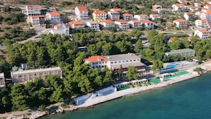 An aerial view of a coastal residential area with multiple buildings, a marina, and a large hotel with a red roof.
