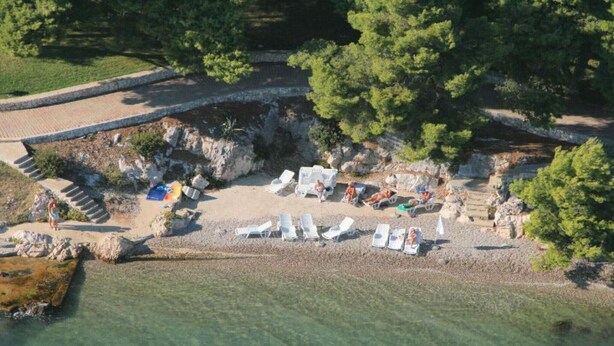 An aerial view of a beach with sun loungers and a few people.