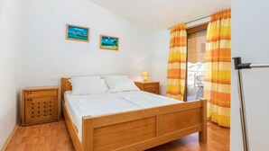 Une chambre à coucher avec un lit en bois, deux tables de chevet, une petite armoire et une fenêtre avec des rideaux à rayures.