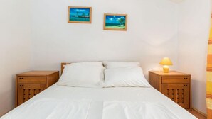 A bedroom with a bed, two nightstands, and two framed pictures on the wall. - Apartments Manda - One Bedroom Apartment With Terrace (A1) (Fazana)