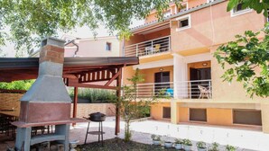Un immeuble résidentiel doté d’un patio comprenant un barbecue, une cheminée et des plantes en pot.