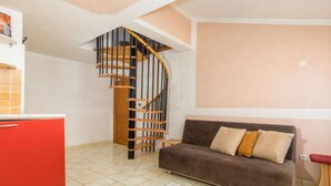 Um espaço de estar compacto com uma escada em espiral, um sofá marrom e um armário vermelho.