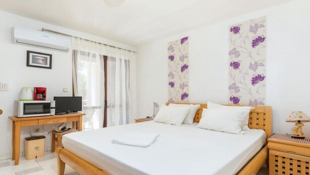 Quarto de hotel com uma cama grande, uma escrivaninha com computador, cafeteira e televisão.