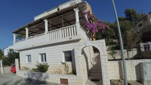 A two-story building with a balcony, a stone archway, and a red car parked in front. - Apartments Maritimo - Comfort Two Bedroom Apartment with Sea View and Terrace (Smokvica)