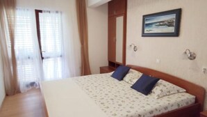 A bedroom with a bed, wooden wardrobe, and a painting on the wall. - Apartments Maritimo - Comfort Two Bedroom Apartment with Sea View and Terrace (Smokvica)