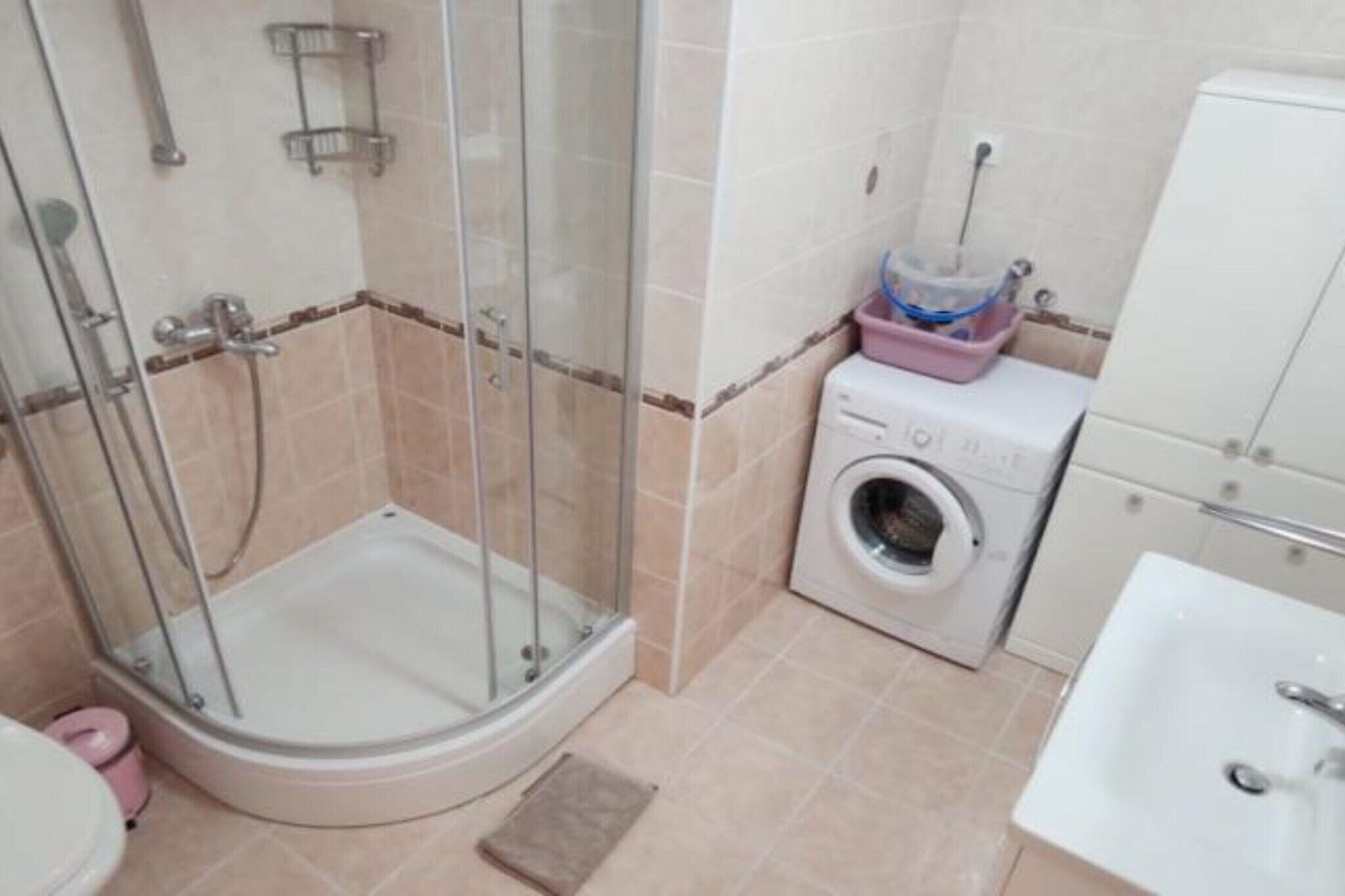 Ein Badezimmer mit Duschkabine, Waschmaschine und Waschbecken.