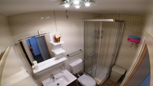 A compact bathroom with a shower, toilet, and sink.