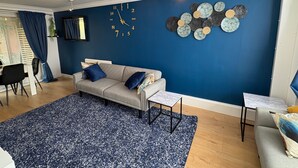 Un salon avec un mur bleu, un canapé, une table basse et une horloge.