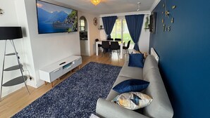 Un salon moderne avec un canapé, un téléviseur et un coin repas.