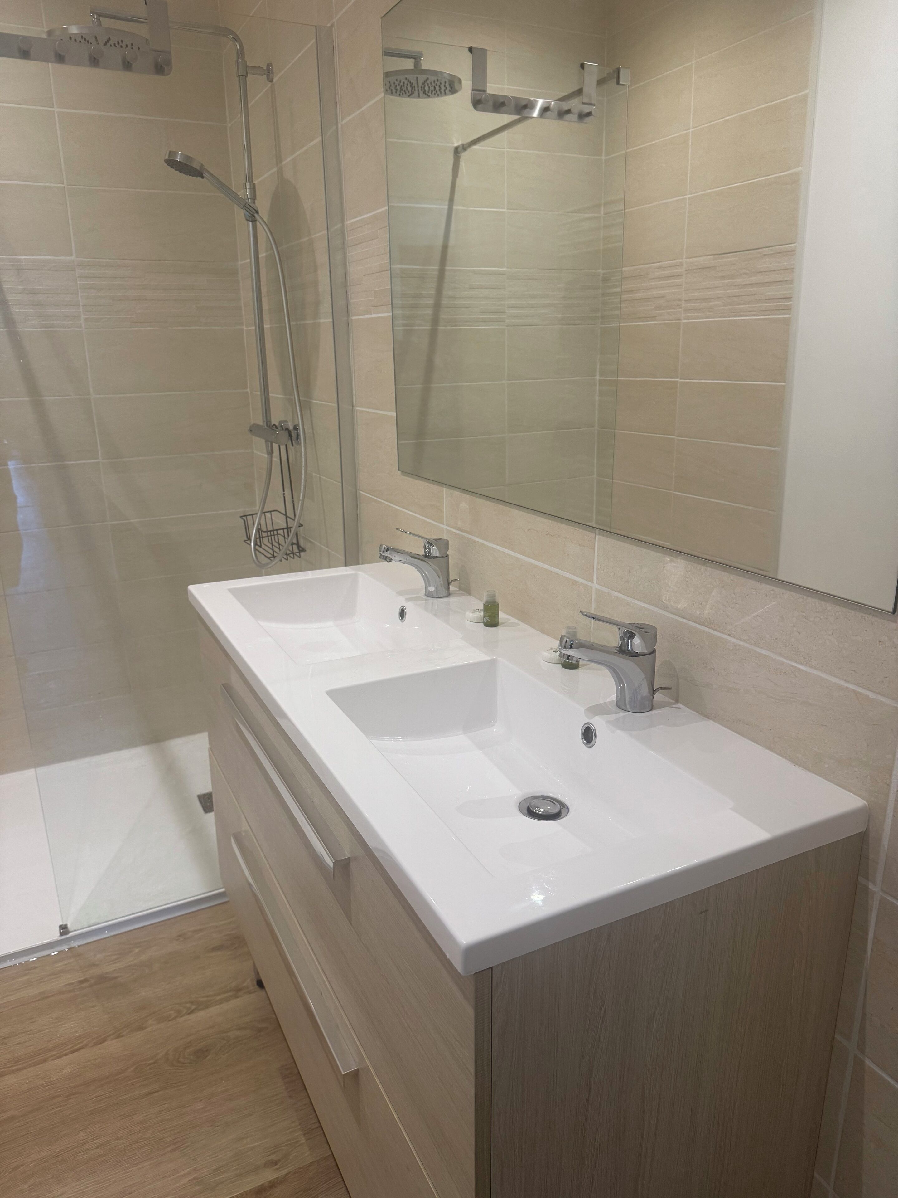Une salle de bain moderne avec deux lavabos, une douche et un grand miroir.