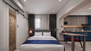 Una habitación de hotel moderna con una cama grande, un área de comedor y una kitchenette.