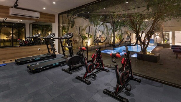 Un gimnasio con cintas de correr, bicicletas estáticas y una zona de piscina.