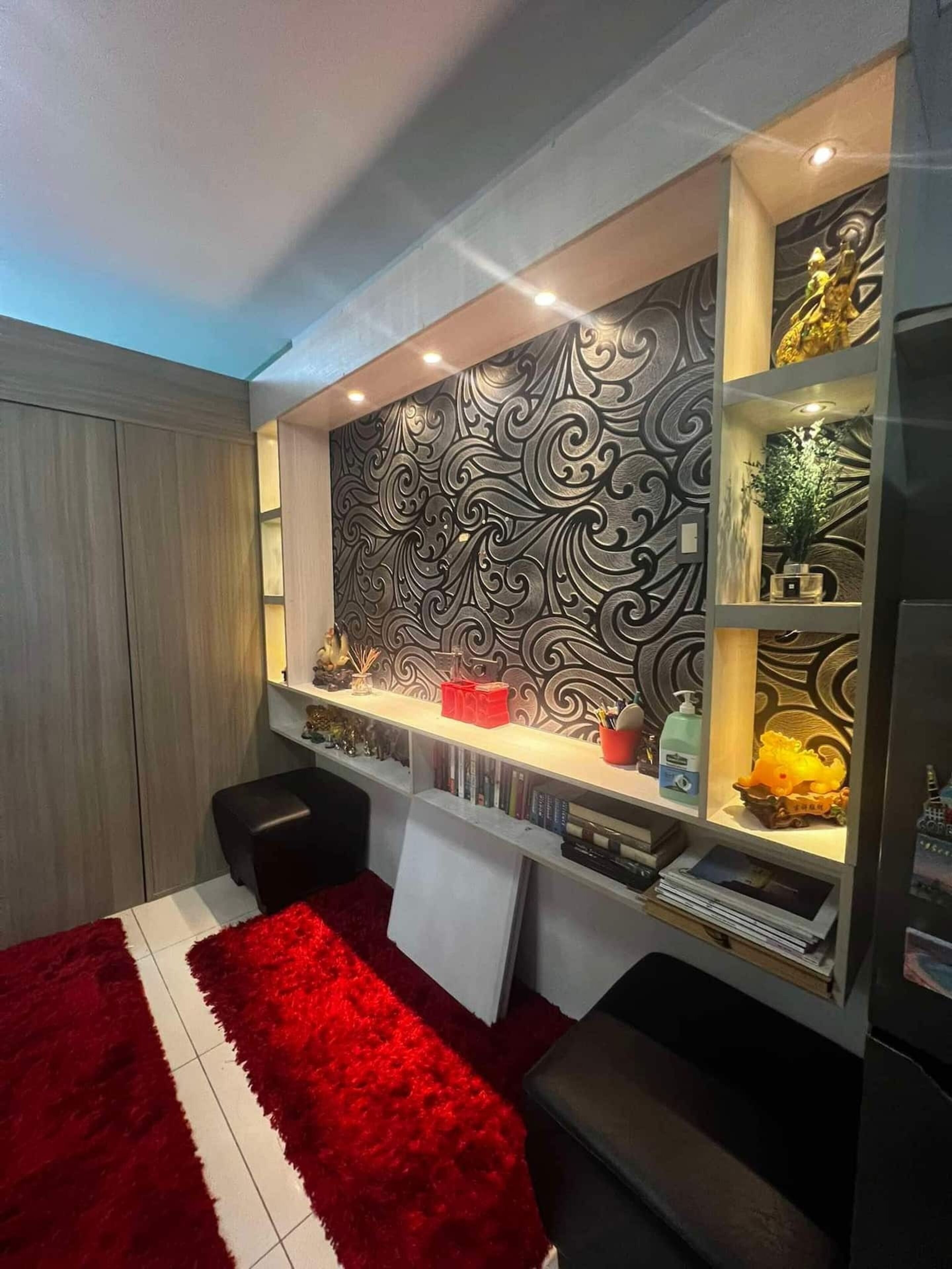 Une chambre moderne avec un mur décoratif, un tapis rouge et une étagère contenant divers objets.